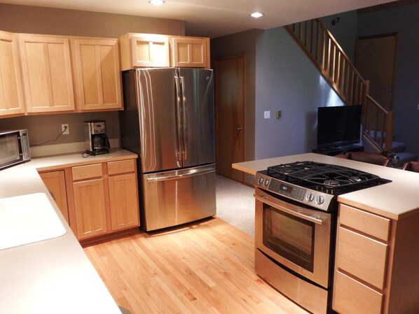 Una cocina moderna con electrodomésticos de acero inoxidable, armarios de madera y piso de madera.