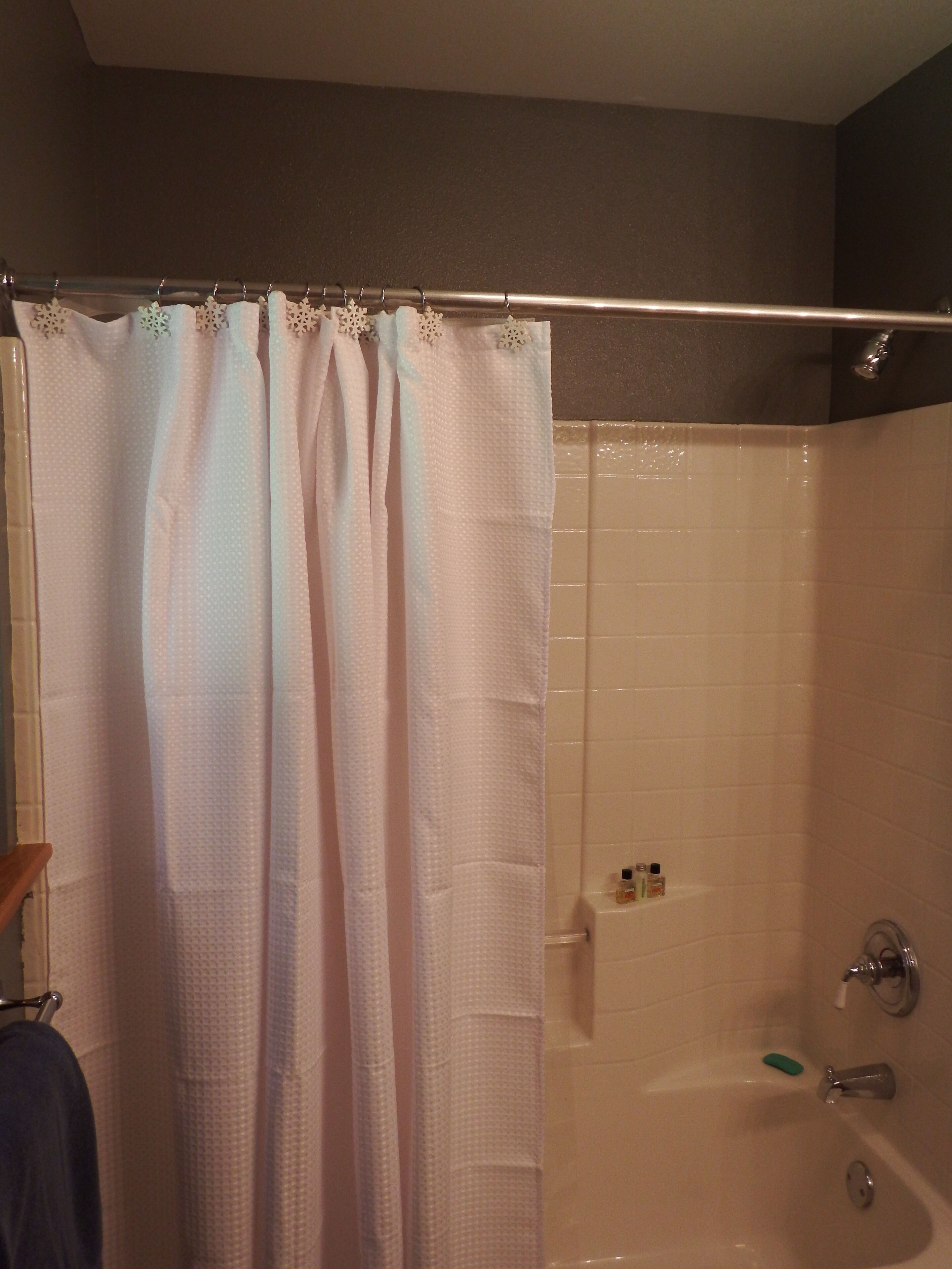 A bathroom with a shower curtain, a bathtub, and a towel rack.
