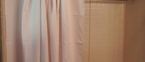 A bathroom with a shower curtain, a bathtub, and a towel rack.