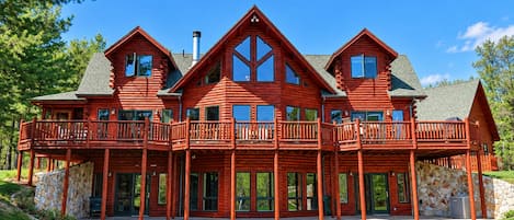 Une grande cabane en rondins dotée de plusieurs balcons et d’une fondation en pierre.