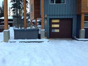 Set amidst a serene winter landscape, this two-story house features a garage door and three windows on the upper floor.