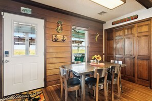 A dining area with a wooden wall, a white door, and a table with chairs.