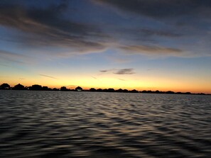 A calm body of water reflecting the sky during sunset.