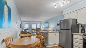 A kitchen with wooden chairs, a stainless steel refrigerator, and a dining table.