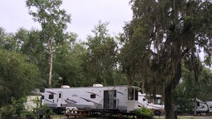 Een camper staat geparkeerd in een camping, omringd door bomen.