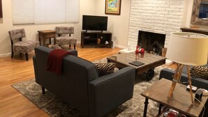 A living room with a fireplace, a television, and two armchairs. - Sonoma Retreat w/ Pool, Spa & Spacious Yard – Near Wineries & Sonoma Plaza (Sonoma)