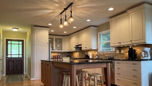 A modern kitchen with wooden cabinetry, a central island with stools, and a hanging light fixture. - An Inspirational View.... (Horse Shoe)