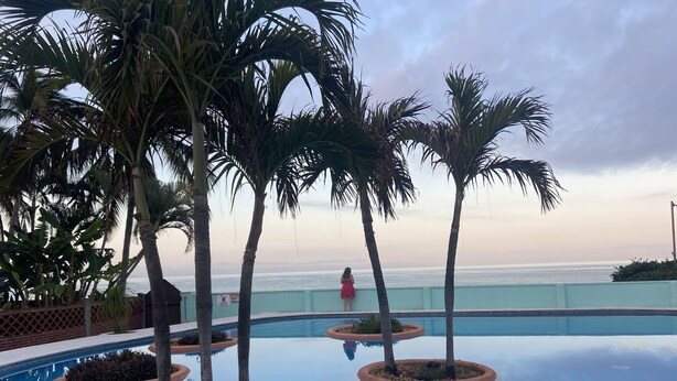 A pool with palm trees, a view of the ocean, and a person in a pink dress. - A pool and a beach… What else do you need? Check out my REVIEWS! GREEN! (BUCERIAS)