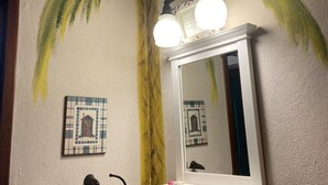 A bathroom with a wall mural of a palm tree, a mirror above a vanity, and a towel rack with a towel. - A pool and a beach… What else do you need? Check out my REVIEWS! GREEN! (BUCERIAS)