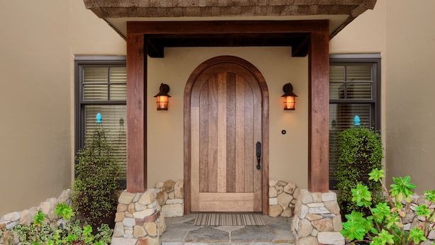 A wooden door with a stone foundation, flanked by two stone pillars and a stone wall. - Pura Vida-Spring Special (Cambria)