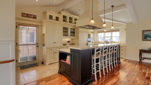 A spacious kitchen with a large island, wooden flooring, and pendant lighting. - Pura Vida-Spring Special (Cambria)