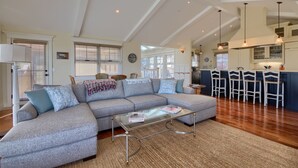 A spacious living room with a sectional sofa, a glass coffee table, and a kitchen area in the background. - Pura Vida-Spring Special (Cambria)