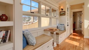 A cozy reading nook with a bench, bookshelves, and a view through large windows. - Pura Vida-Spring Special (Cambria)