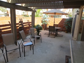Relax in the enclosed patio area with a table and four chairs, surrounded by a brick wall and a pergola.