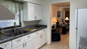 Une cuisine moderne avec des meubles blancs, un plan de travail en granit et un motif décoratif représentant des poissons sur le mur.