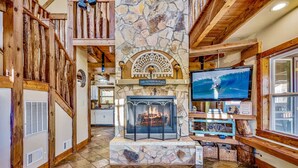 A stone fireplace with a sign above it, a television on the wall, and wooden beams on the ceiling. - Private with large yard, community pool , fishing, game room, pets, easy access  (Sevierville)