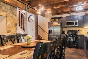 A modern kitchen with stainless steel appliances, wooden accents, and a dining area with a table set for four. - Renovated , private . Pool , fish. Easy access, pets , CHRISTMAS available ~ (Sevierville)