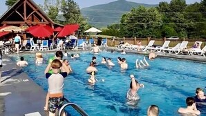 A swimming pool area with people swimming and sunbathing. There are lounge chairs and umbrellas around the pool. - Private with large yard, community pool , fishing, game room, pets, easy access  (Sevierville)
