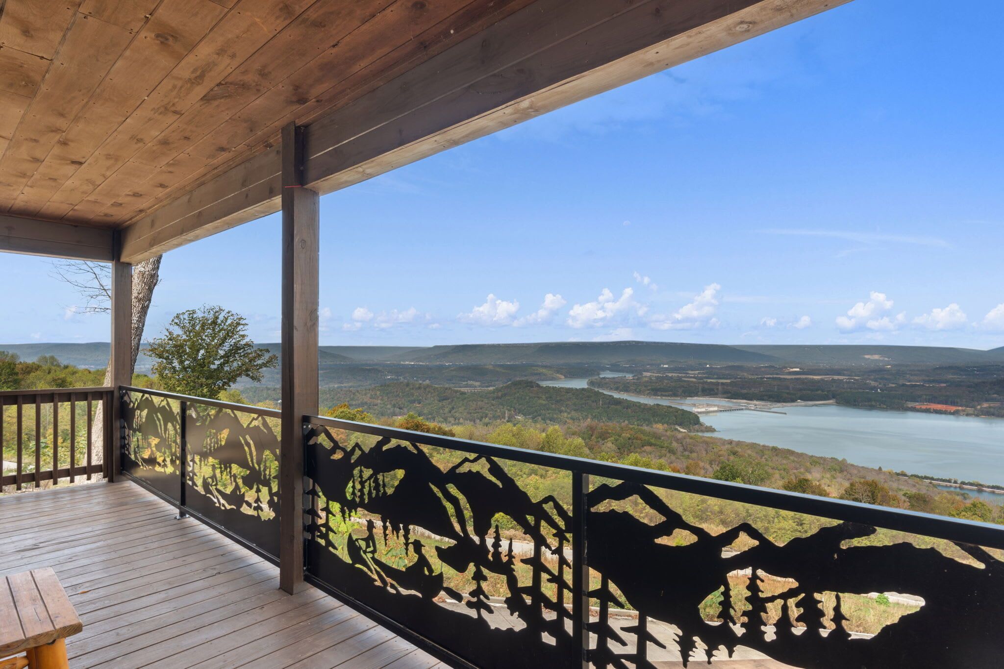A wooden deck with a view of a river and hills.
