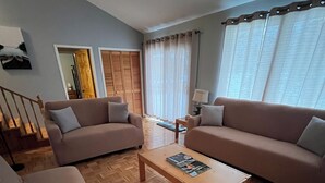 A living room with two sofas, a coffee table, a wooden floor, a staircase, and a door leading to another room. - Muskoka, Cozy 2 Bedroom / 2 Bathroom Cottage located on the coveted Lake of Bay (Dwight)