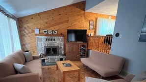 A living room with a stone fireplace, wooden walls, and a television. - Muskoka, Cozy 2 Bedroom / 2 Bathroom Cottage located on the coveted Lake of Bay (Dwight)