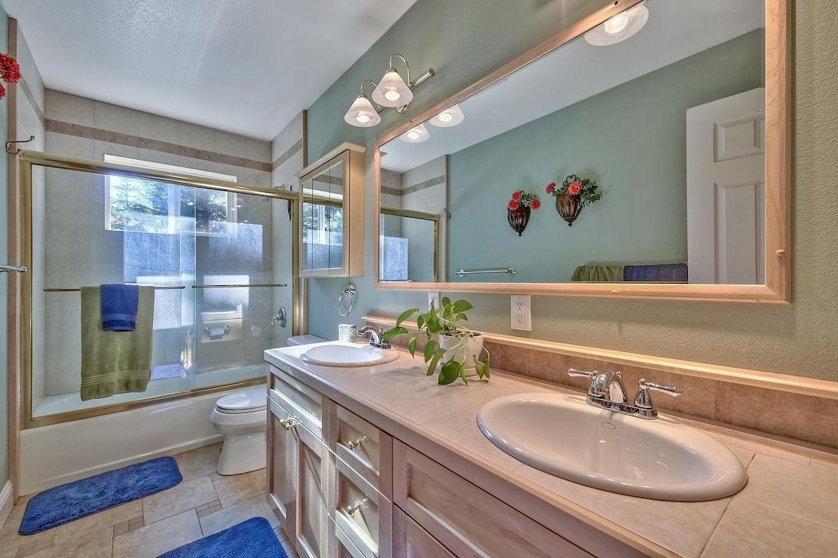A modern bathroom with a glass-enclosed shower, dual sinks, and a large mirror.