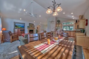 Amplia sala de estar con una gran mesa de comedor de madera, asientos cómodos, chimenea y televisor.
