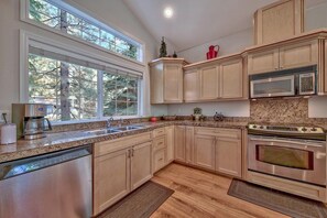 A kitchen with a dishwasher, double sink, granite countertop, wooden cabinets, and a stainless steel oven. - Where Eagles Fly, Hot Tub, Pets ok, great spot (South Lake Tahoe)