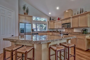 A kitchen with a large island, wooden cabinets, and bar stools.