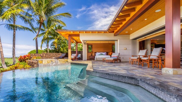 A poolside area with a clear pool, lounge chairs, and a covered seating area.