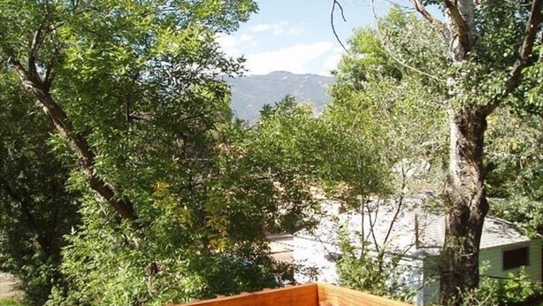 A wooden deck with a view of a mountainous landscape and trees. - Historic Westside Home: Central Location, AC & Game Room (Colorado Springs)