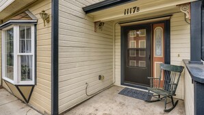 A house with a dark front door, a mailbox, and a small porch with a rocking chair. - Historic Westside Home: Central Location, AC & Game Room (Colorado Springs)