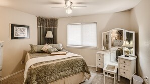 A bedroom with a bed, a dresser, a mirror, a lamp, a ceiling fan, and a window. - Historic Westside Home: Central Location, AC & Game Room (Colorado Springs)