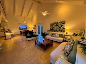 A spacious living area with a sofa, coffee table, and a dining area with chairs.