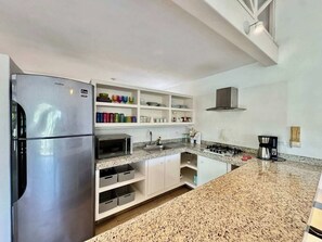 A modern kitchen with a stainless steel refrigerator, granite countertops, white cabinetry, and a built-in microwave.