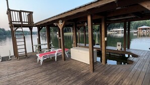 A wooden deck with a covered seating area, a ladder, and a small pool.