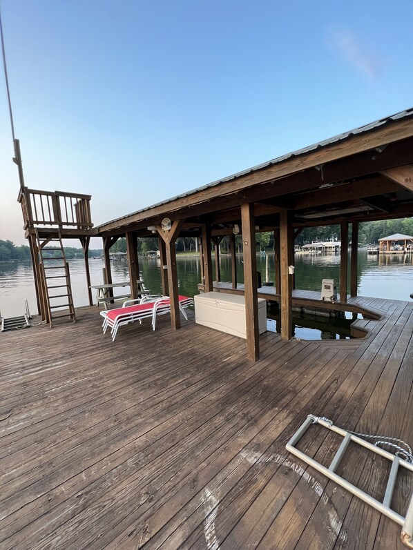 A wooden deck with a covered seating area, a ladder, and a small pool.