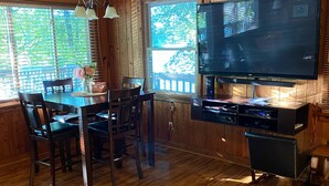 A wooden cabin interior with a dining area, a television, and a sign indicating 'LAKE'.