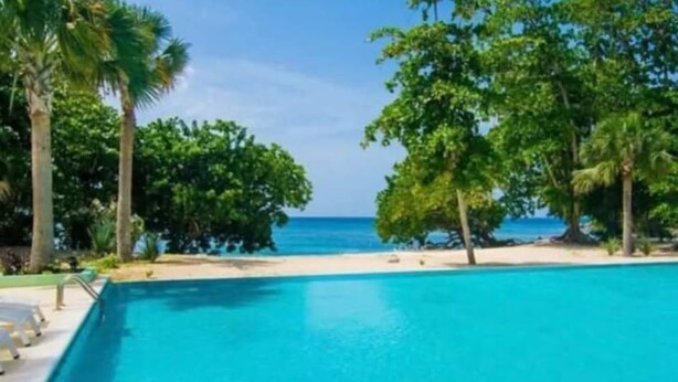 A clear view of a swimming pool with a view of the ocean and palm trees. - CHARMING 2 BEDROOM HOME: 3 BEDS, SLEEPS 1-5, 24hr SECURITY, PRIVATE POOL & BEACH (Negril)