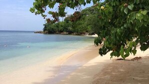 A beach with clear turquoise water, sandy shore, and lush greenery. - CHARMING 2 BEDROOM HOME: 3 BEDS, SLEEPS 1-5, 24hr SECURITY, PRIVATE POOL & BEACH (Negril)