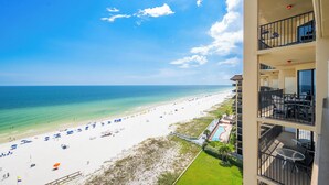 A beachfront hotel with balconies overlooking the ocean, a pool, and beach umbrellas. - Beautiful 2BR Gulf Front Condo - Phoenix V 1106 (Orange Beach)