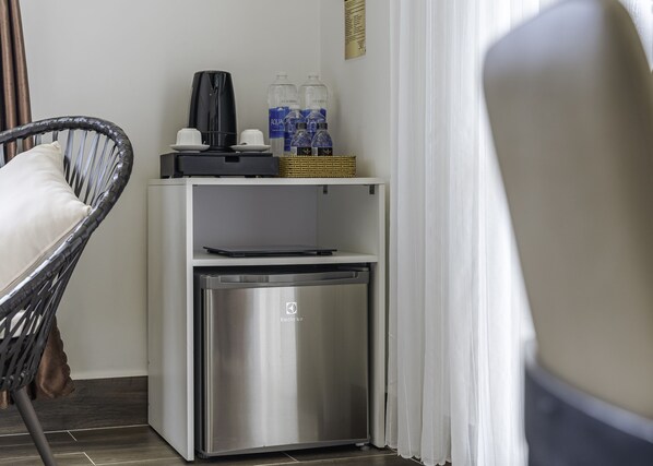 A compact kitchenette with a coffee maker, water bottles, and a small refrigerator. - Minh Chien Hotel (Xuan Huong - Da Lat)