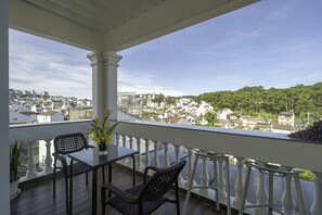A balcony with a table and chairs, overlooking a cityscape with buildings and greenery. - Minh Chien Hotel (Xuan Huong - Da Lat)