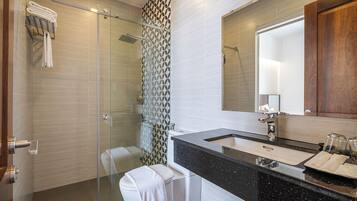 A modern bathroom with a glass shower enclosure, a black granite sink, and a large mirror.