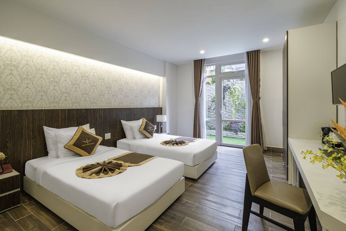 Une chambre d’hôtel avec deux lits, un bureau et une chaise.