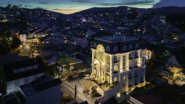 A historic building with a prominent clock tower, surrounded by residential buildings and a hilly landscape.