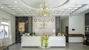 A hotel reception area with a marble reception desk, a chandelier, and a reception counter. - Minh Chien Hotel (Xuan Huong - Da Lat)