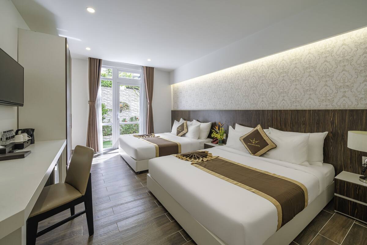 Une chambre d’hôtel avec deux lits, un bureau et une télévision.