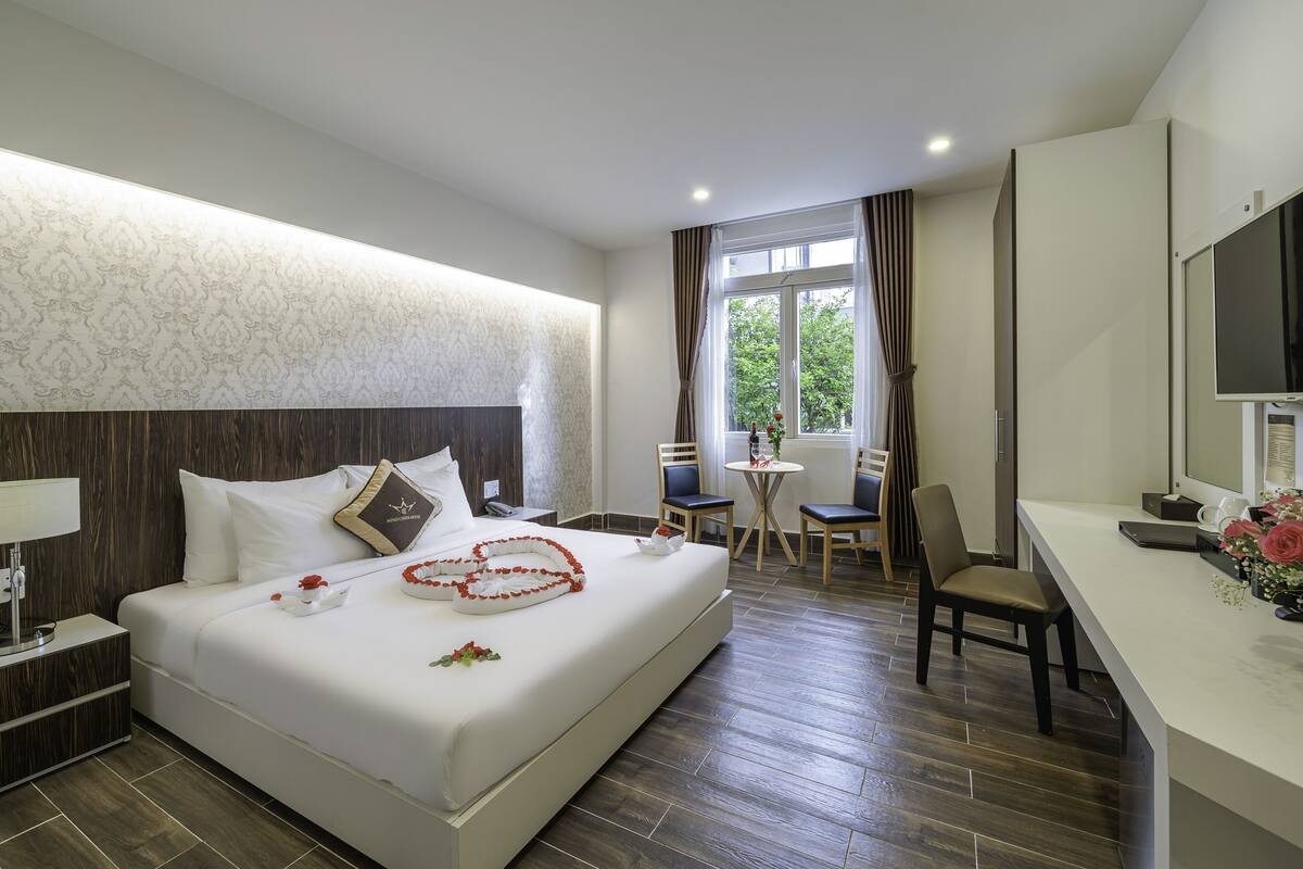 Une chambre d’hôtel avec un grand lit, un bureau, une chaise et une petite table.