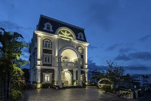 Un hotel elegante con una entrada en arco destacada, un balcón y una fachada bien iluminada.